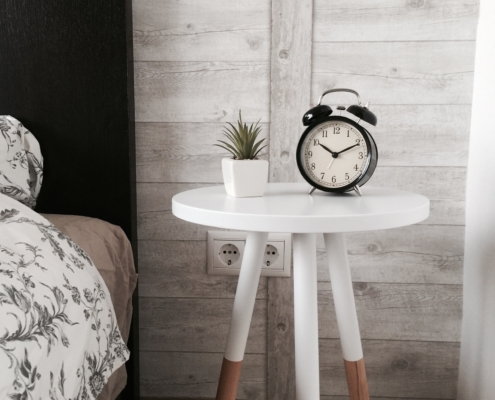 black alarm clock at 10:10 on white wooden table near table