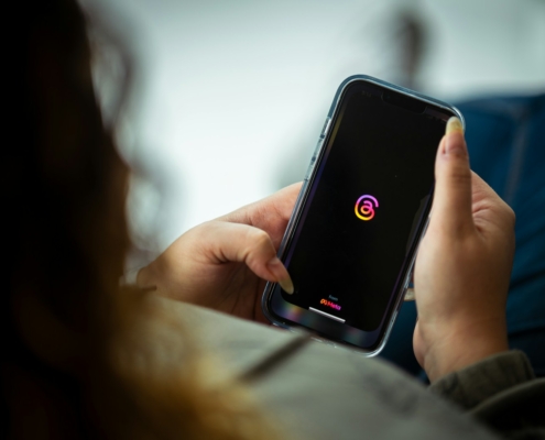 Einführung in Threads: Ein Leitfaden für den Neuen Sozialen Medienkanal a woman holding a cell phone with a logo on it