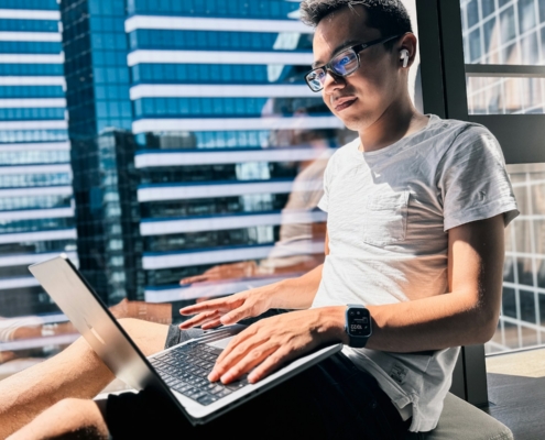 freelancer sitting in front of a window using a laptop computer