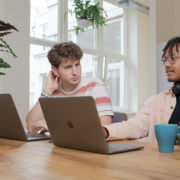 man and woman sitting at table using macbook