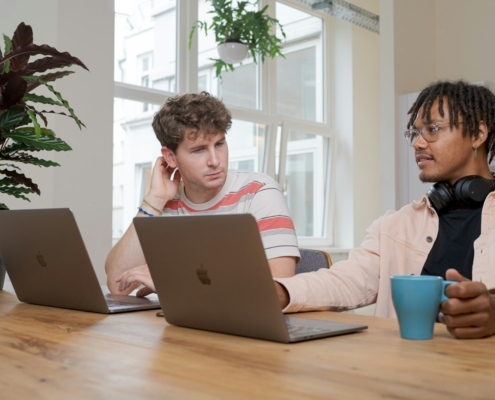 man and woman sitting at table using macbook