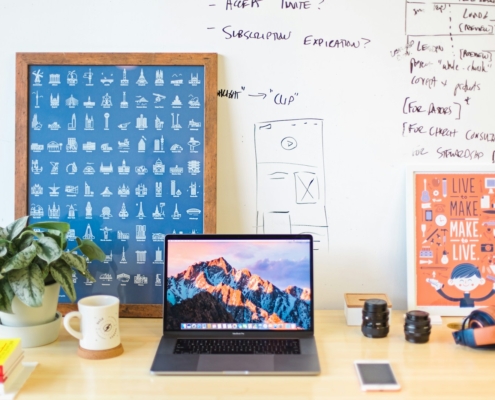 MacBook Pro on brown wooden table beside white mug