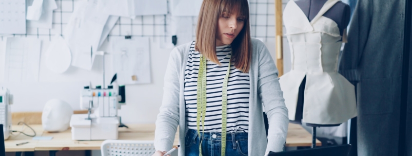 A fashion designer works at a laptop.