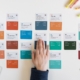 a person's hand on a piece of paper next to a bunch of colored