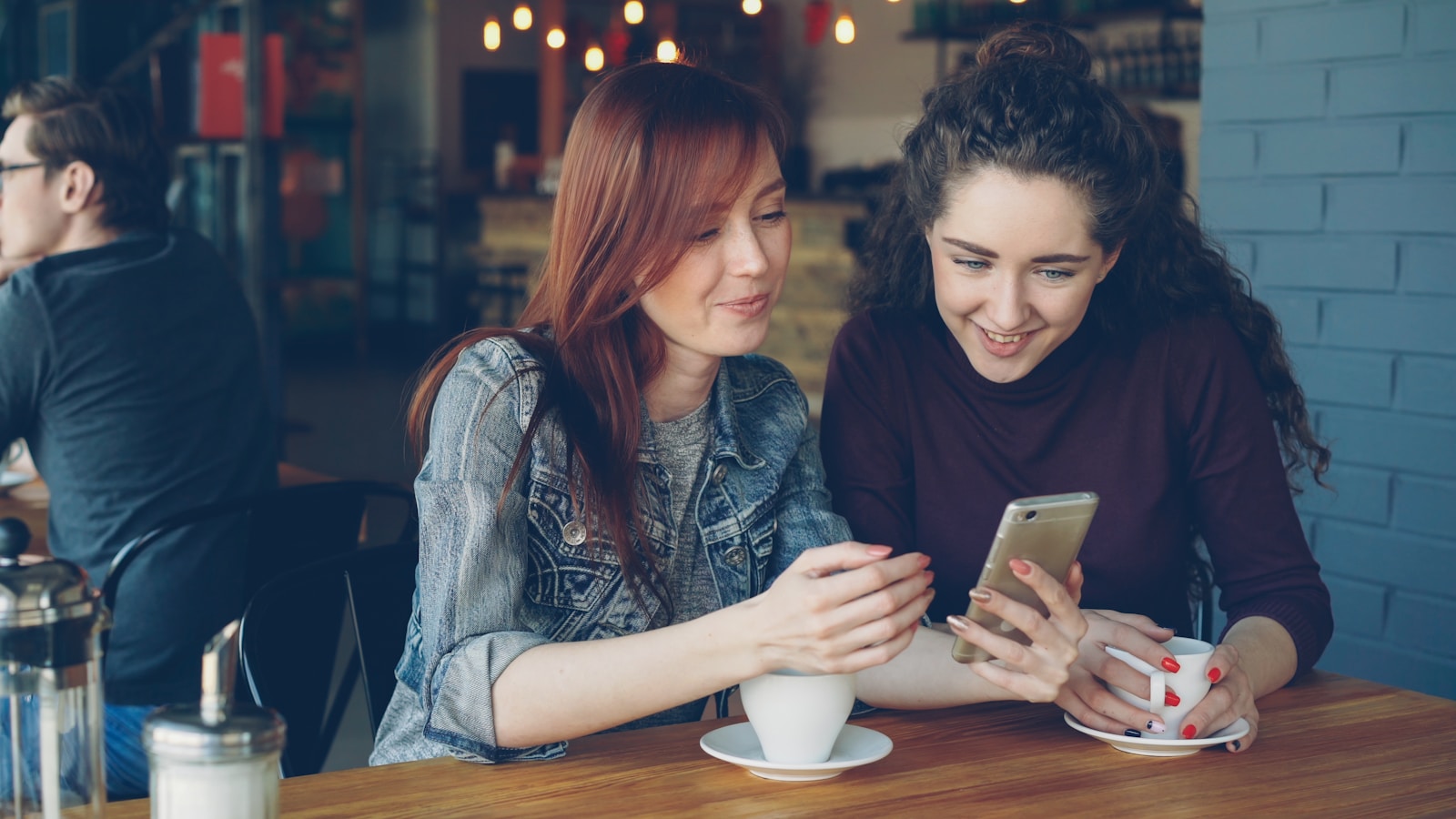 Two friends happily look at a phone together.