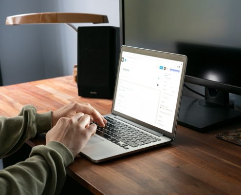 person in gray jacket using macbook pro