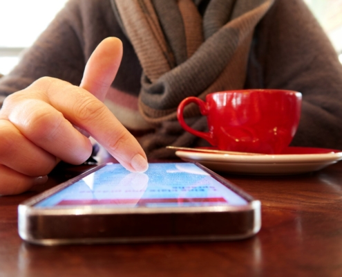 Person using a smartphone with a cup of coffee.